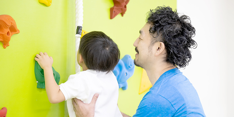 ボルダリングを教えるスタッフと子供